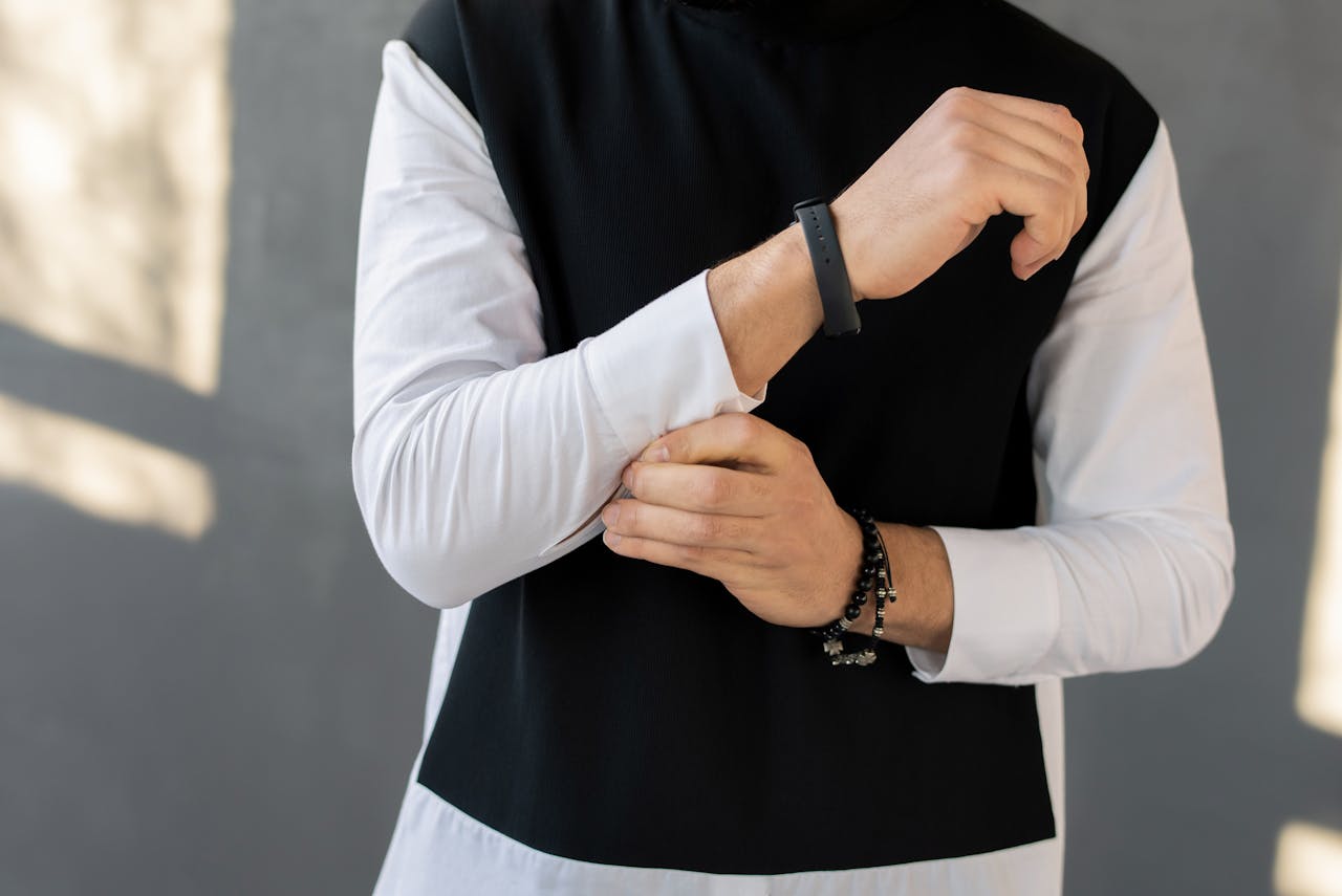 Close-up of a man adjusting his sleeve with a fashionable bracelet, showcasing modern style.